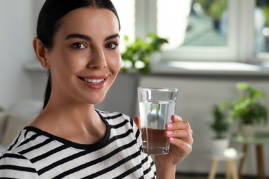 Photo of Young woman with glass of water indoors, closeup. Refreshing drink
