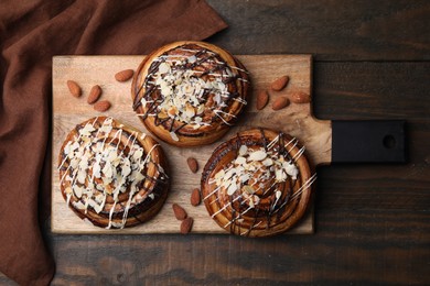 Photo of Delicious rolls with toppings and almonds on wooden table, top view. Sweet buns