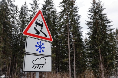 Warning traffic signs near forest road. Winter driving