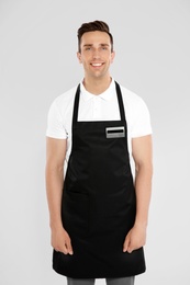 Photo of Portrait of handsome waiter in apron on light background
