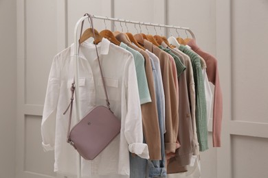 Rack with stylish women's clothes near light wall