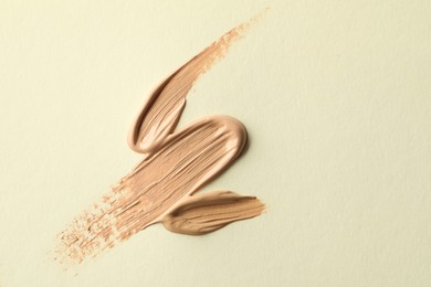 Photo of Samples of liquid skin foundations on beige background, top view