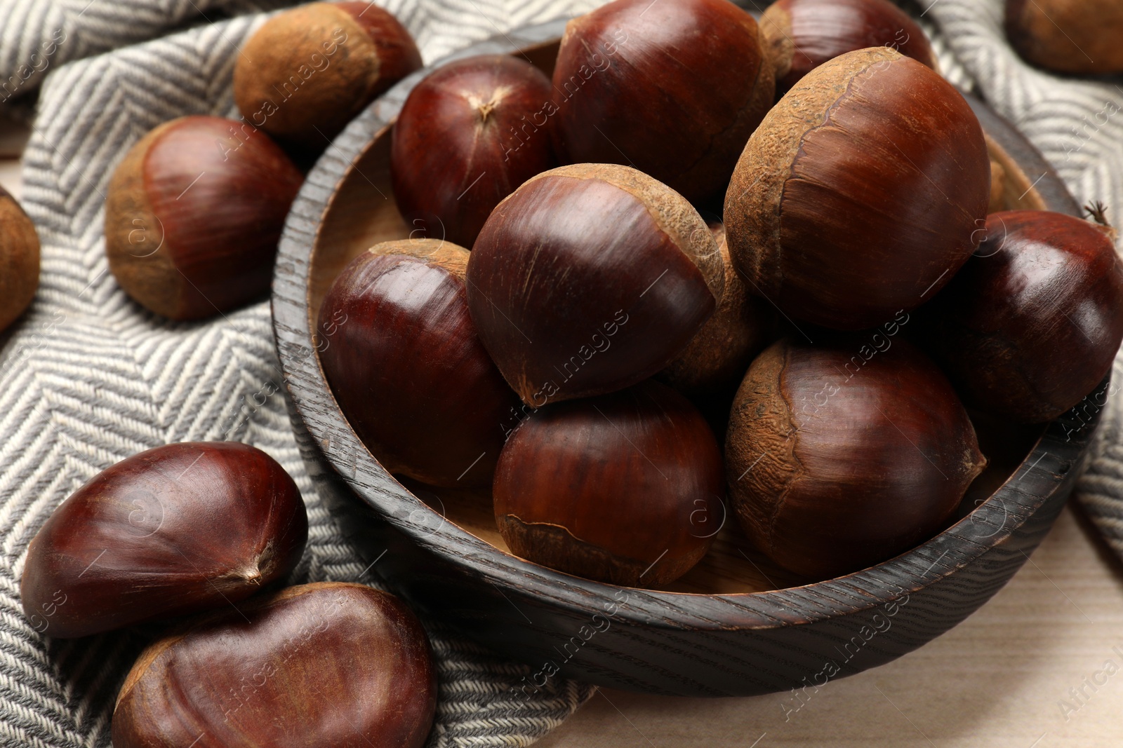 Photo of Sweet fresh edible chestnuts on light wooden table, closeup