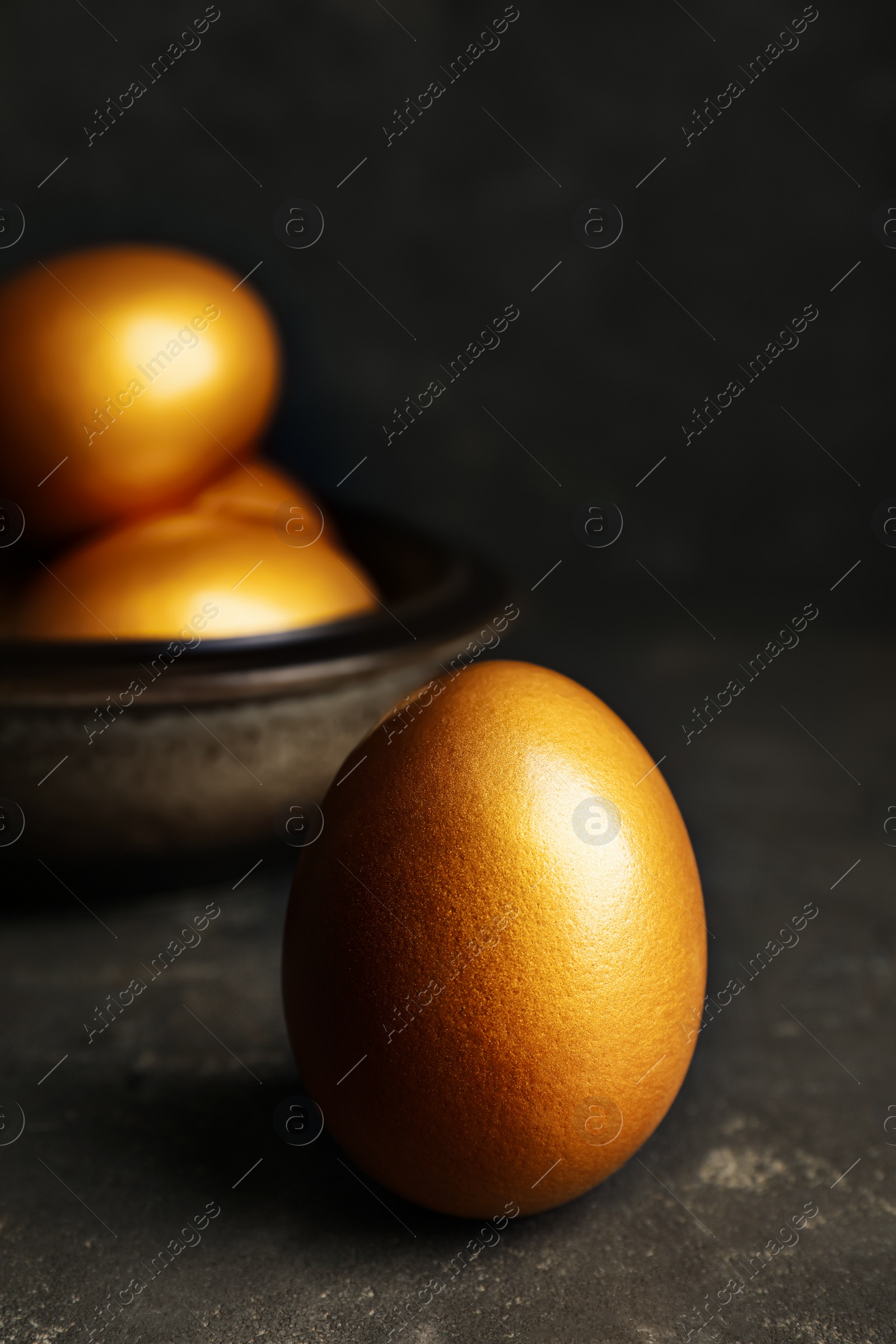 Photo of Golden egg on black table, closeup view