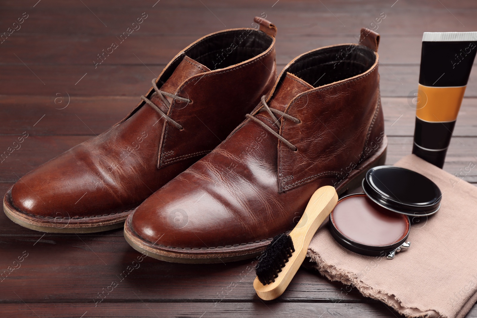 Photo of Shoe care accessories and footwear on brown wooden table, closeup