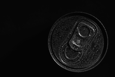 Aluminum can of beverage covered with water drops on black background, top view. Space for text
