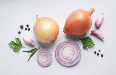Flat lay composition with onions and spices on light background