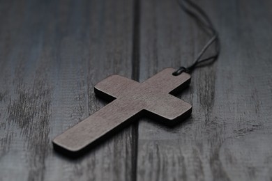 Photo of Christian cross on black wooden table, closeup