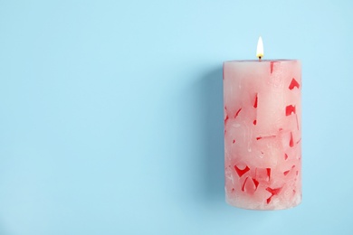 Photo of Alight wax candle and space for text on color background