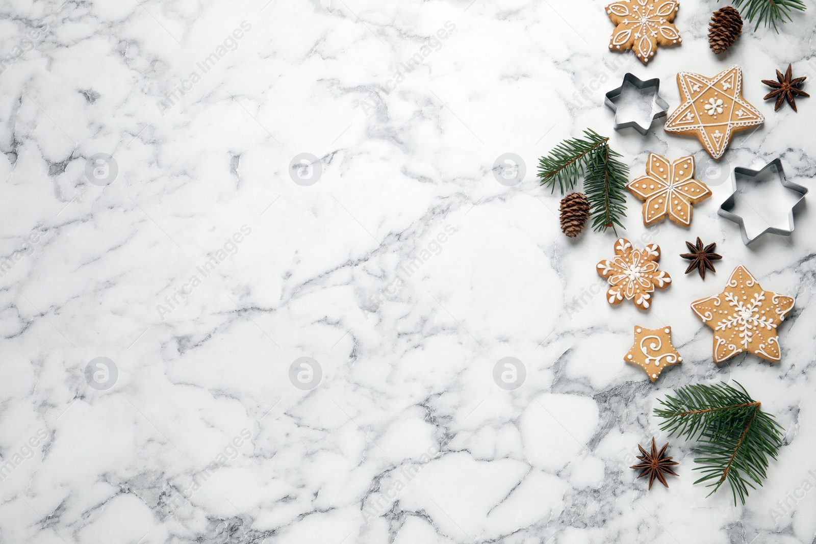 Photo of Tasty Christmas cookies, cutters and fir branches on white marble table, flat lay. Space for text