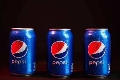 MYKOLAIV, UKRAINE - FEBRUARY 08, 2021: Cans of Pepsi with water drops on color background