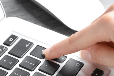 Photo of Woman pressing button on laptop keyboard, closeup