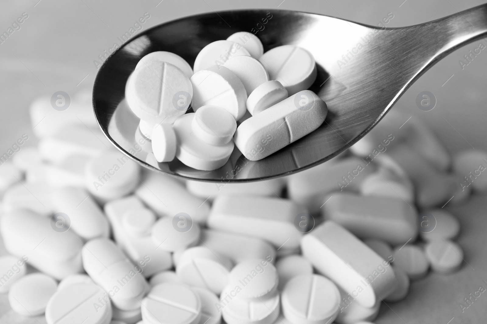 Photo of Spoon with weight loss pills over table, closeup