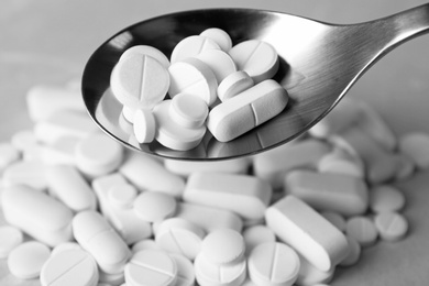 Photo of Spoon with weight loss pills over table, closeup