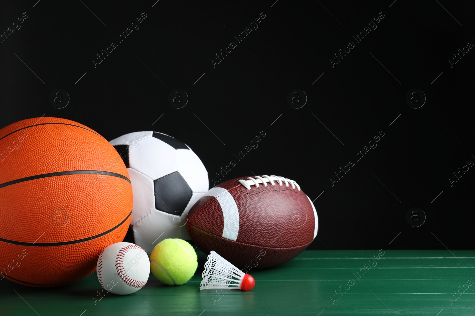 Photo of Set of different sport balls and shuttlecock on green wooden surface. Space for text
