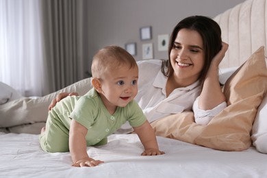 Photo of Happy young mother and cute baby crawling on bed at home