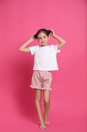 Photo of Cute girl in pajamas on pink background