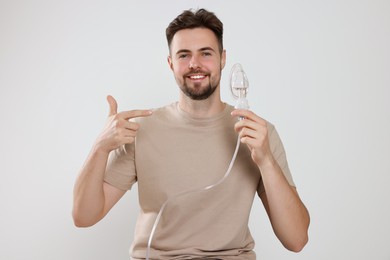 Photo of Man holding nebulizer for inhalation on beige background