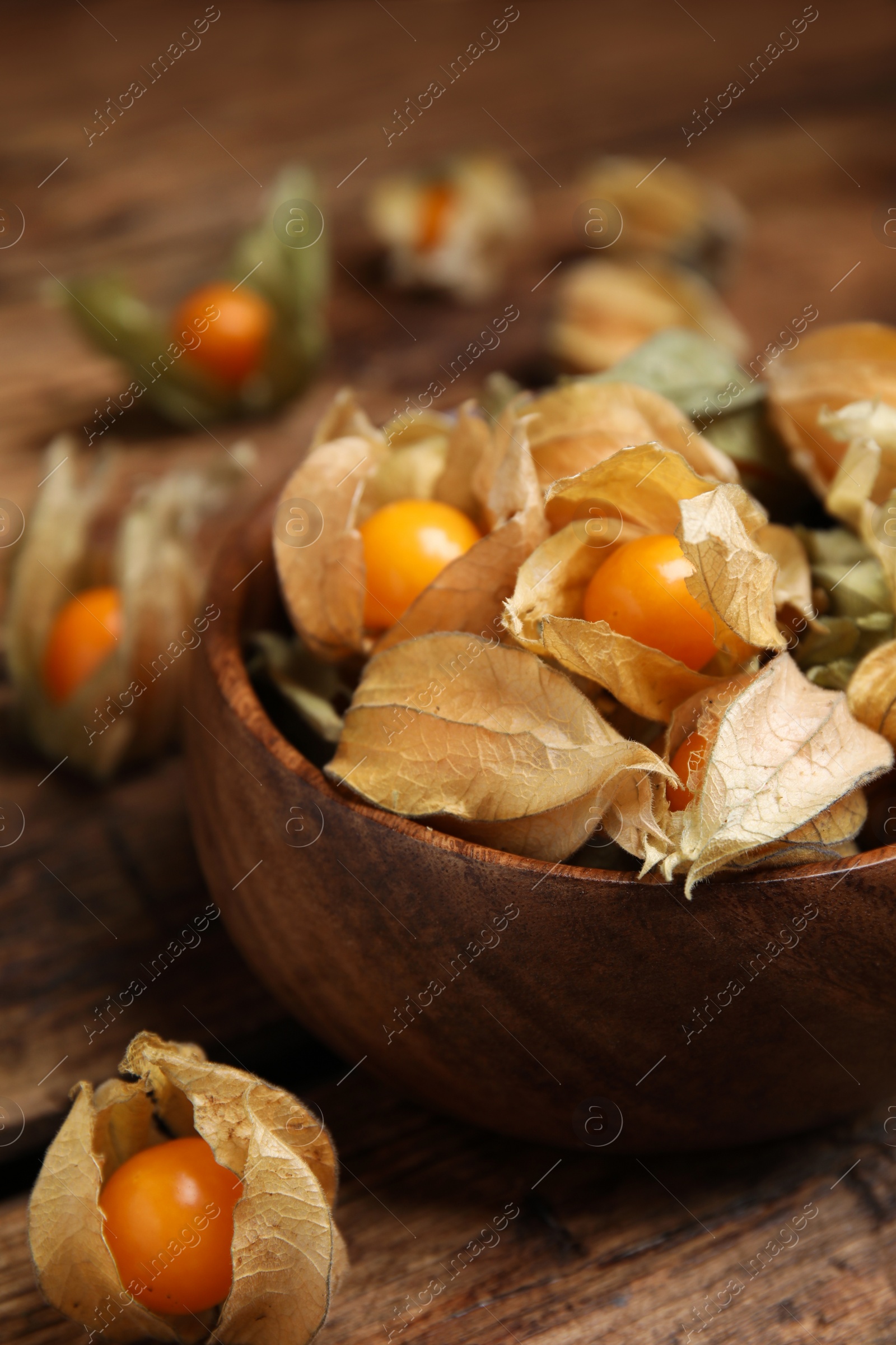 Photo of Ripe physalis fruits with dry husk on wooden table, closeup