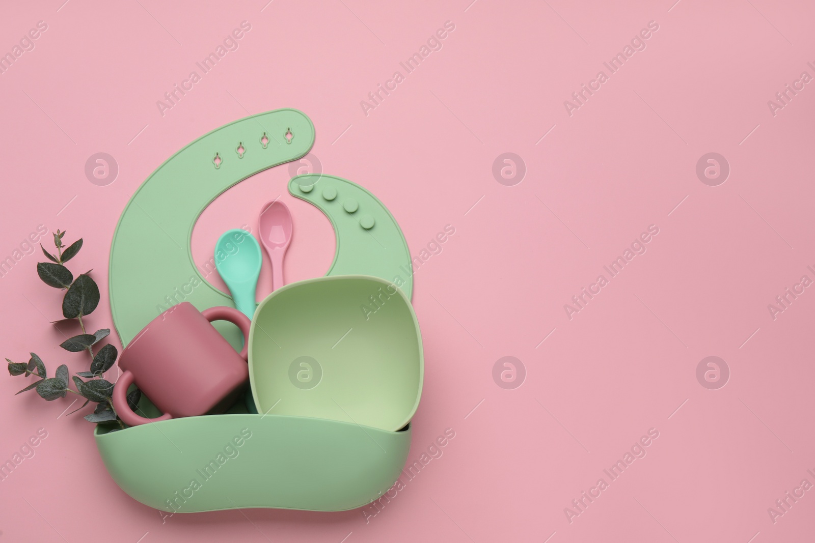 Photo of Baby feeding accessories and bib on pink background, top view. Space for text