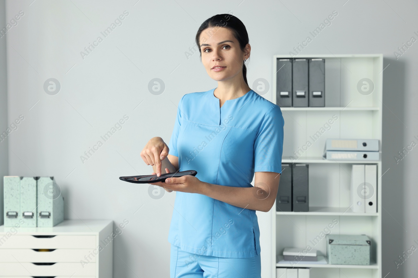 Photo of Beautiful female orthopedist showing insole in hospital