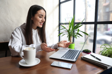 Young blogger working with laptop in cafe