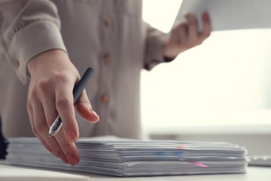 Photo of Woman reading documents at table in office, closeup