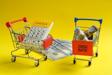 Calculator and dollar banknotes in shopping carts on yellow background. Cashback concept