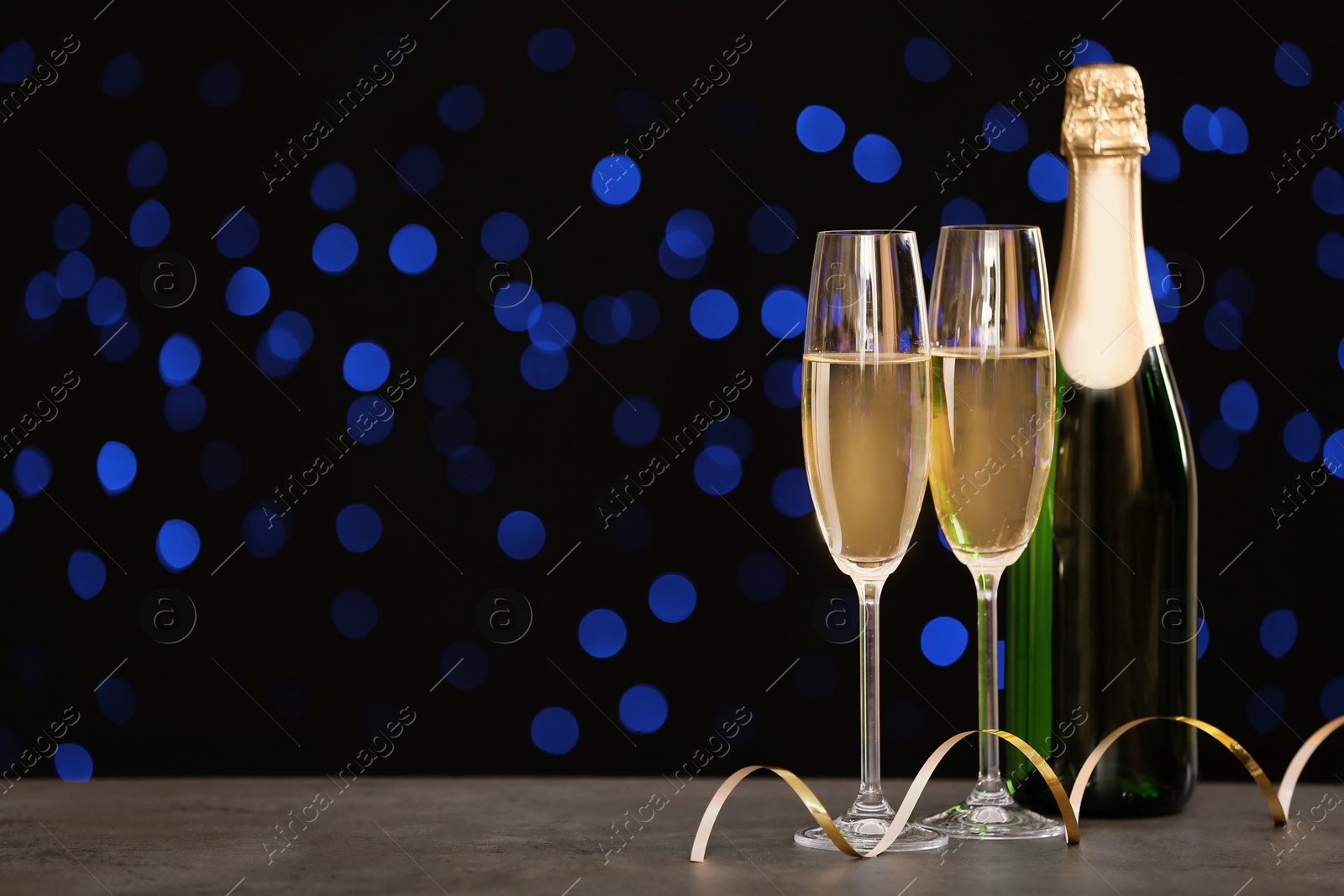 Photo of New year composition with champagne and space for text against blurred Christmas lights