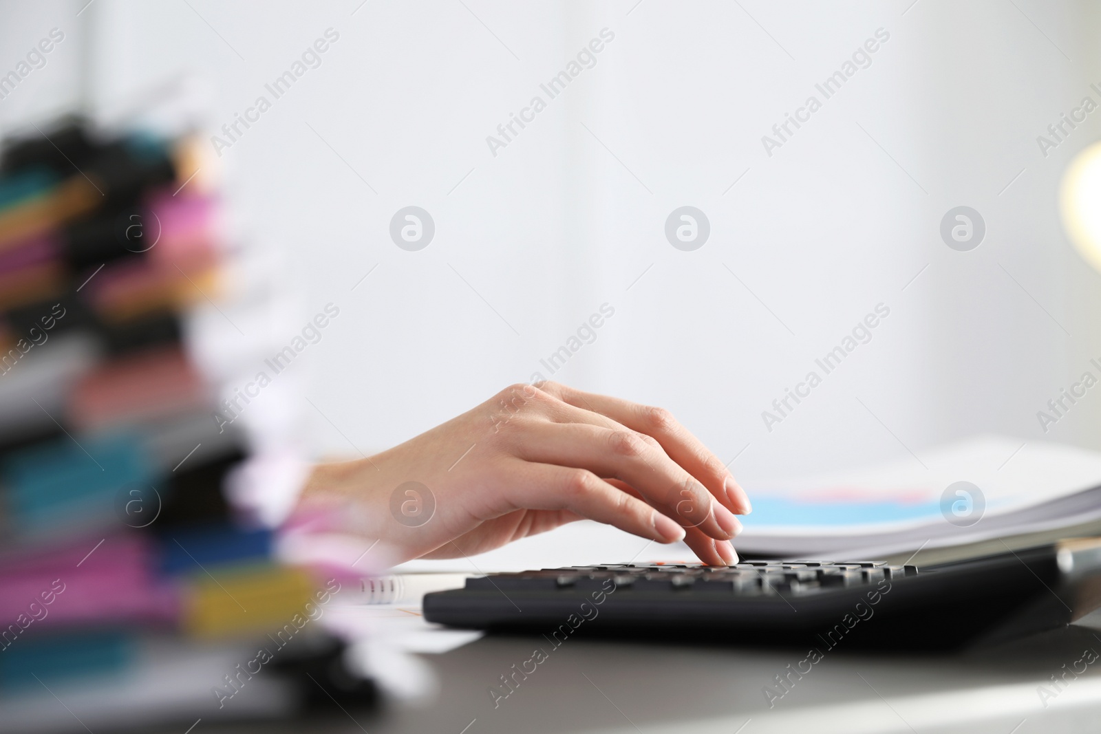 Photo of Office employee working with calculator and documents at table, closeup