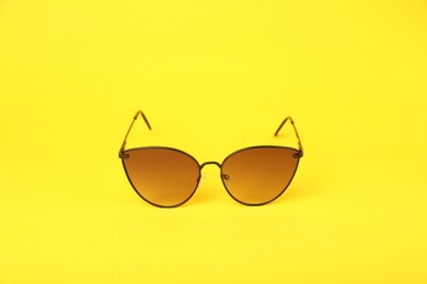 Stylish pair of sunglasses on yellow background