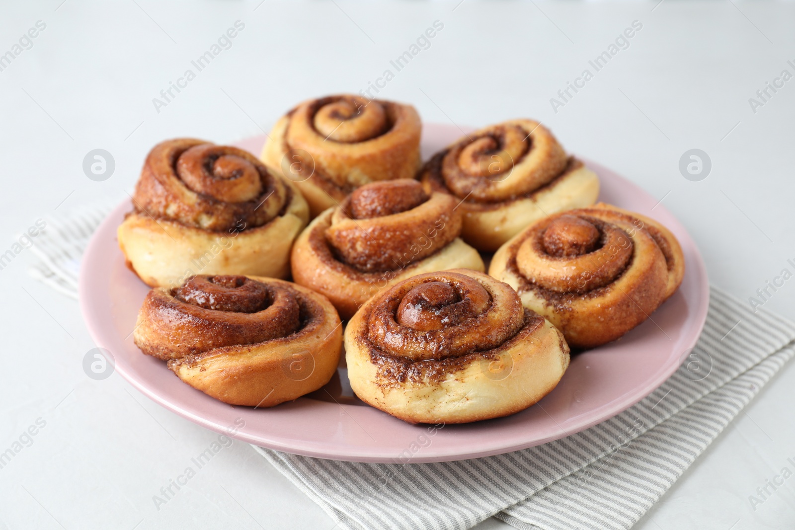 Photo of Many tasty cinnamon rolls on white table, closeup