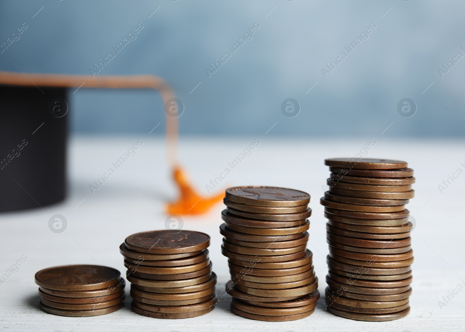 Photo of Coins and student graduation hat on white wooden table. Tuition fees concept