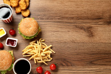 Photo of Flat lay composition with delicious fast food menu on wooden table. Space for text