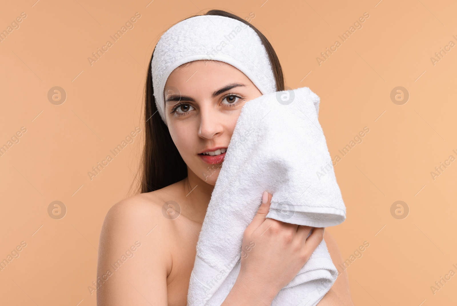Photo of Washing face. Young woman with headband and towel on beige background