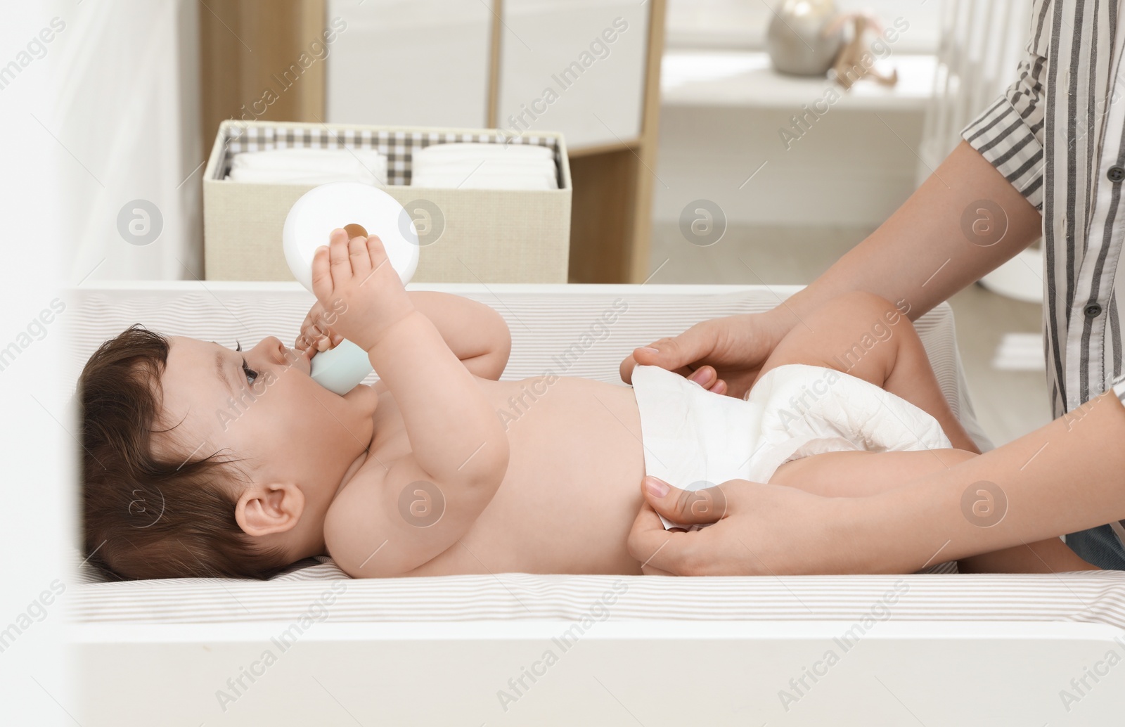 Photo of Mother changing baby's diaper on table at home, closeup