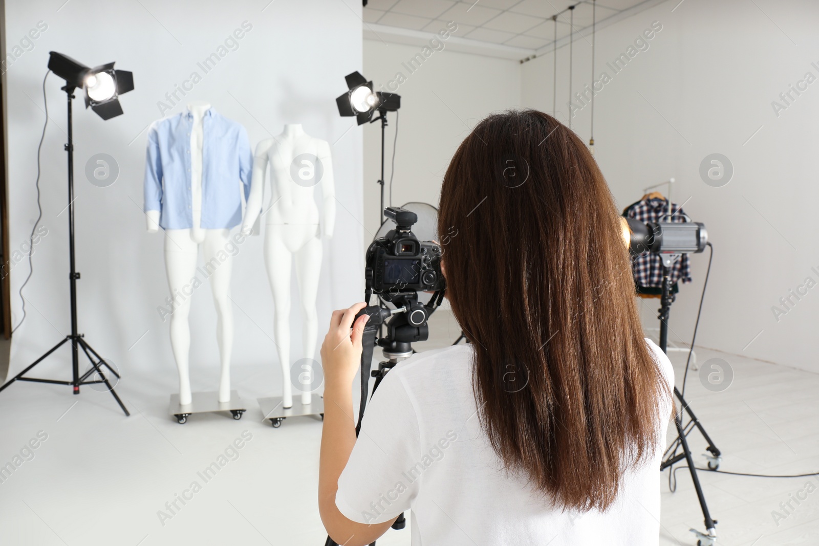 Photo of Professional photographer taking picture of ghost mannequins with modern clothes in photo studio