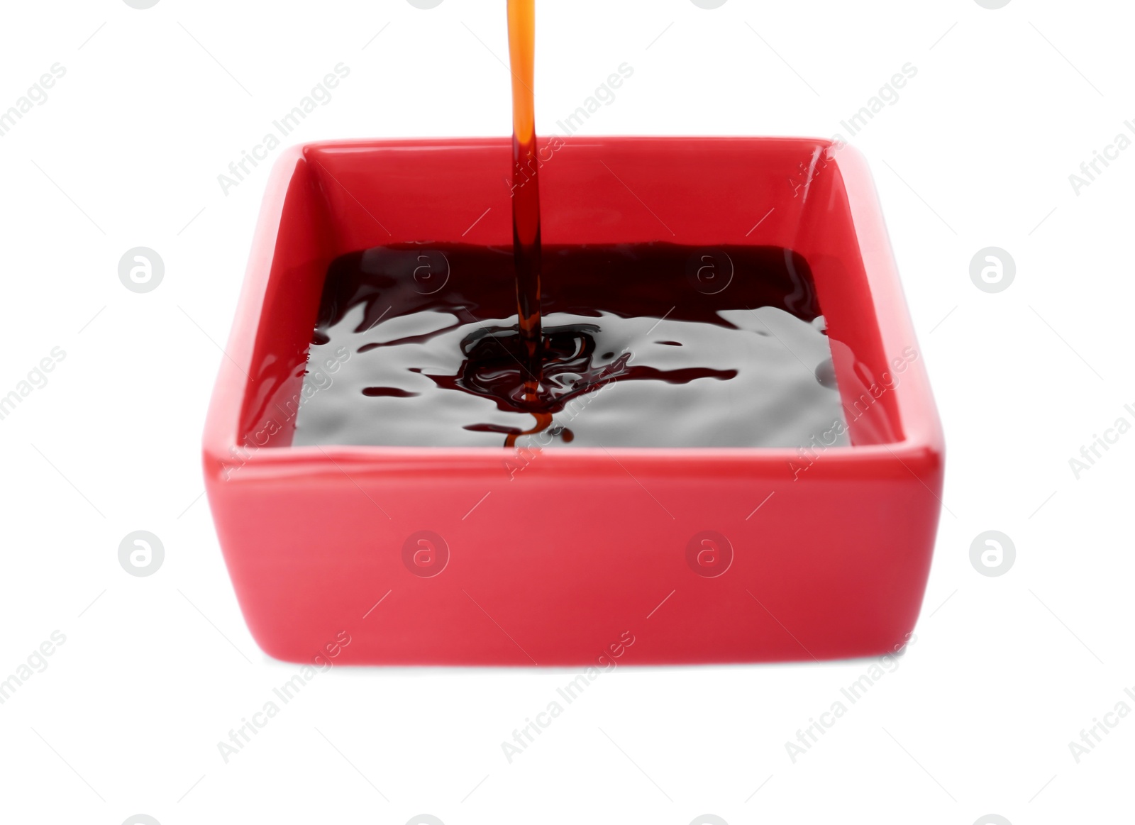 Photo of Pouring tasty soy sauce into bowl isolated on white