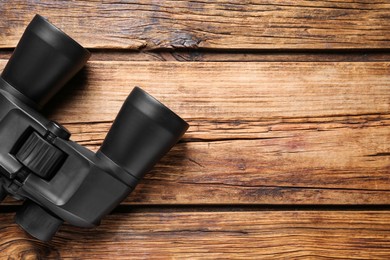 Photo of Binoculars on wooden table, top view. Space for text