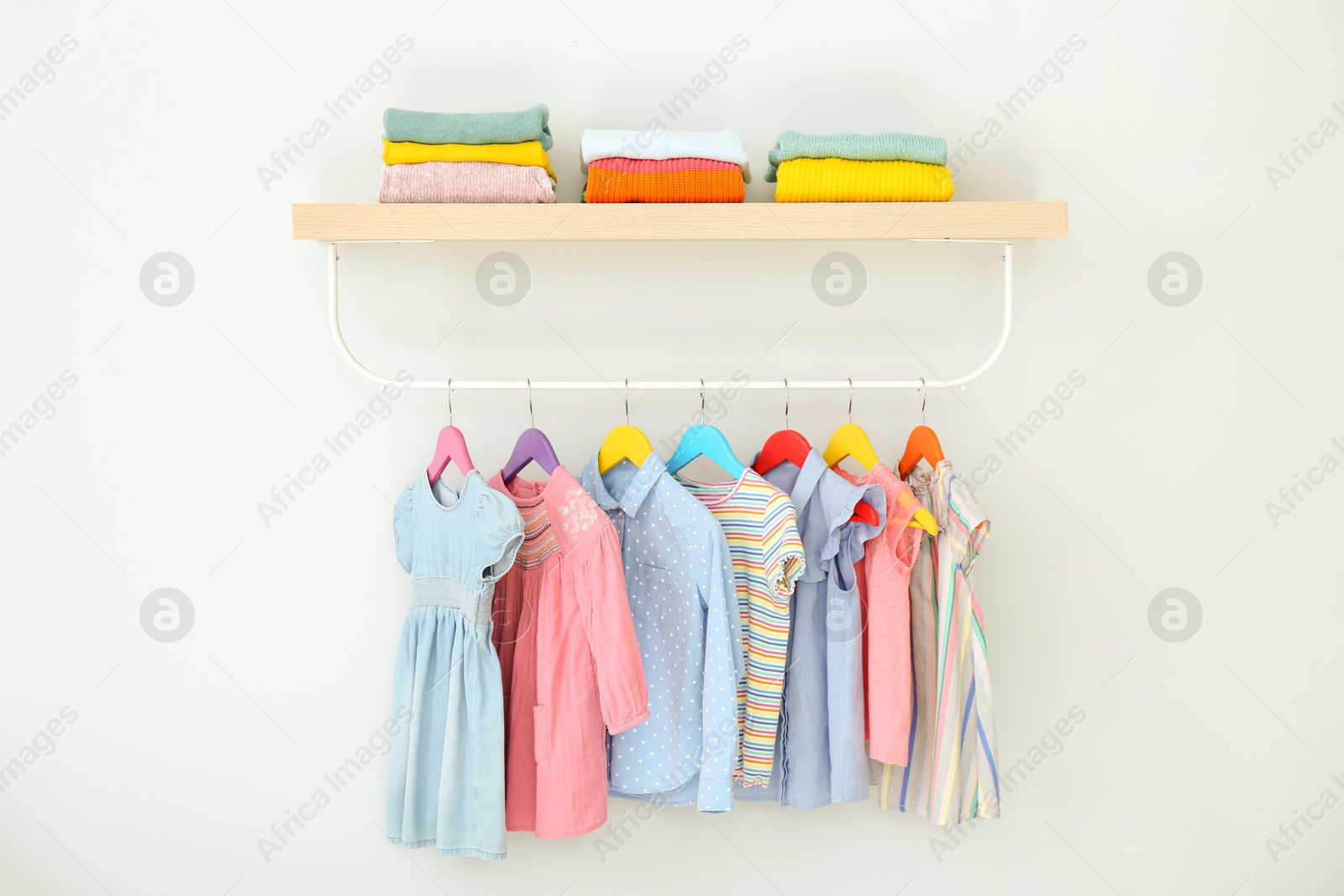 Photo of Rack with different clothes on light background