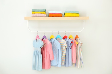 Photo of Rack with different clothes on light background