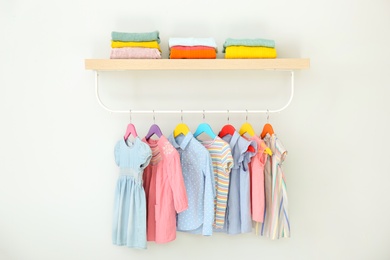 Rack with different clothes on light background