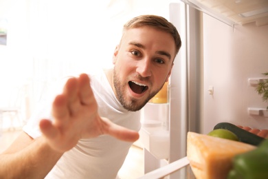 Photo of Young man choosing food in refrigerator, view from inside