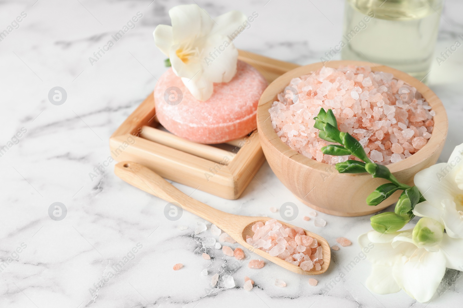 Photo of Beautiful spa composition with sea salt, soap bar and flowers on white marble table. Space for text