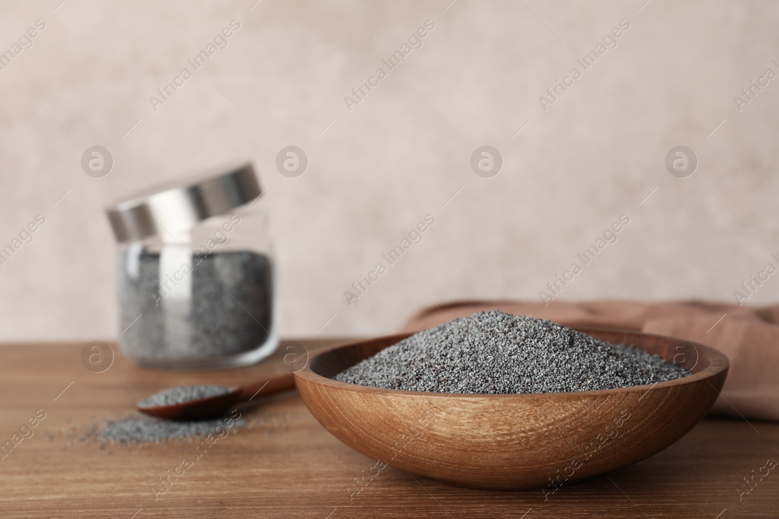 Photo of Poppy seeds in plate on wooden table. Space for text