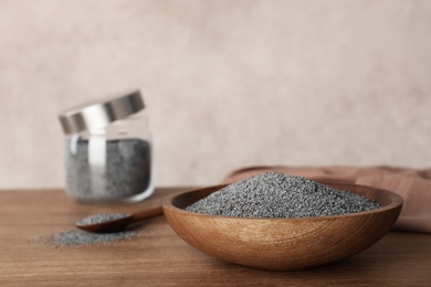 Photo of Poppy seeds in plate on wooden table. Space for text