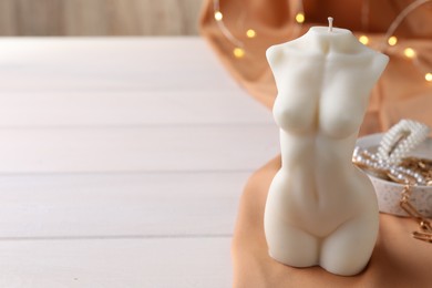 Composition with beautiful female body shaped candle on white table. Space for text