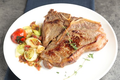 Delicious fried beef meat and vegetables on grey table