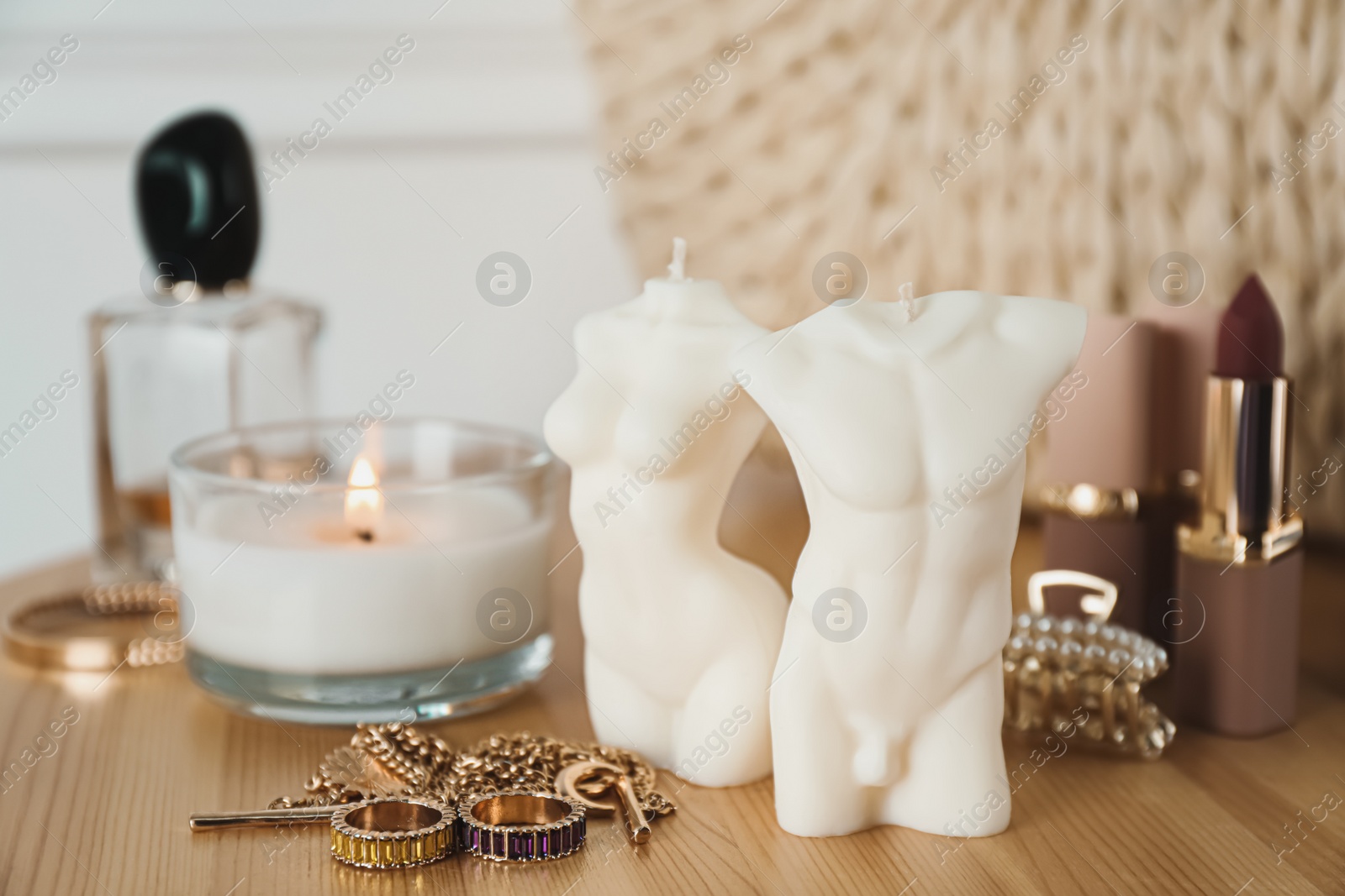 Photo of Beautiful female and male body shaped candles on wooden table. Stylish decor