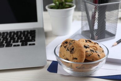 Photo of Bowl with chocolate chip cookies on white wooden table in office. Space for text